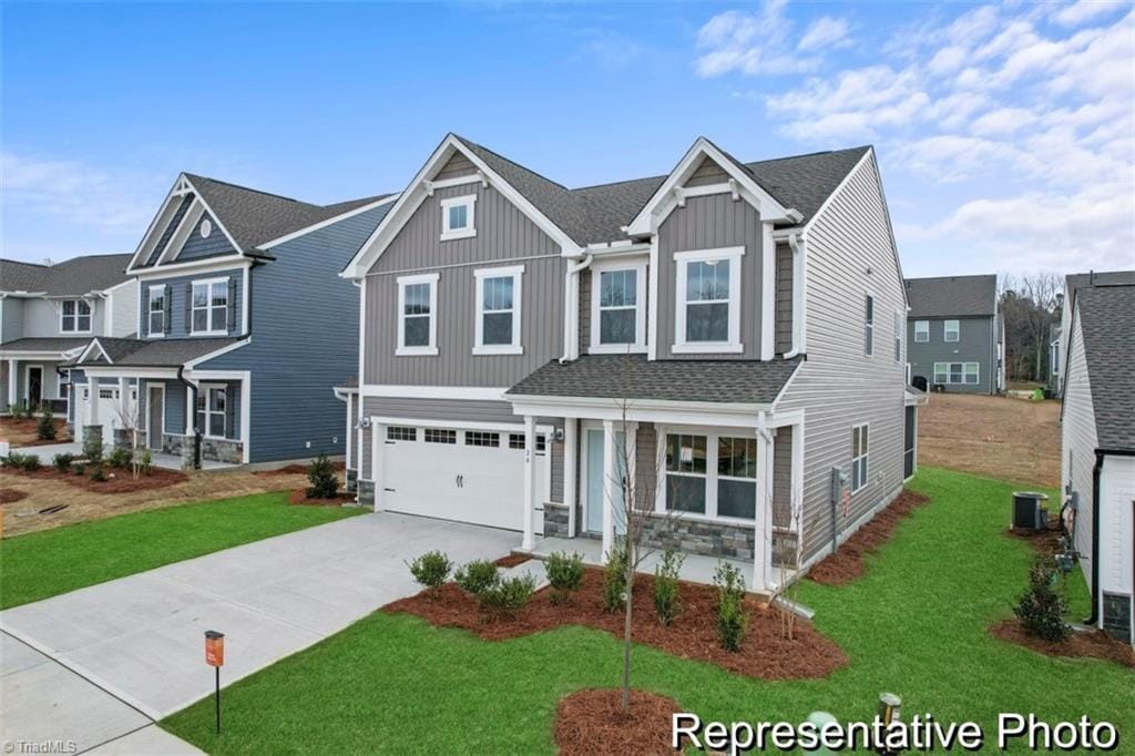 view of front of home featuring a garage, central AC unit, and a front yard