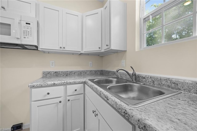 907 Caldwell St, Greensboro, NC 27406 - kitchen featuring white microwave, a sink, white cabinets, and light countertops