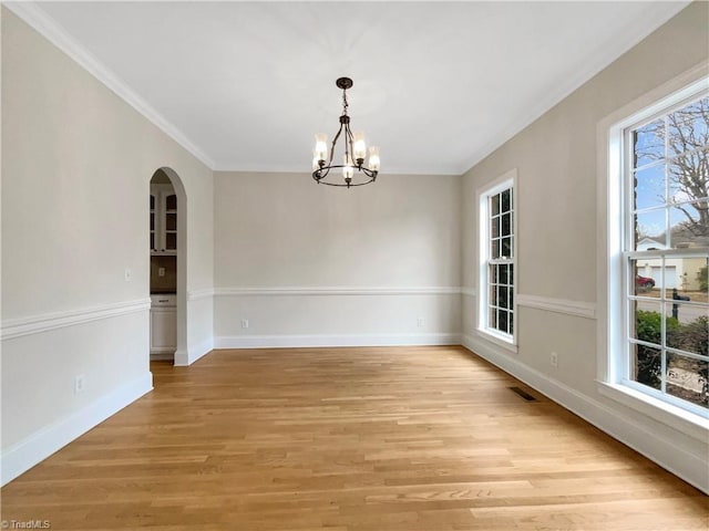 spare room featuring crown molding, a chandelier, and light hardwood / wood-style floors