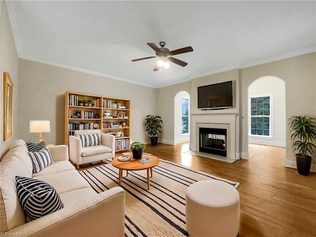 living room featuring hardwood / wood-style flooring, ceiling fan, and ornamental molding