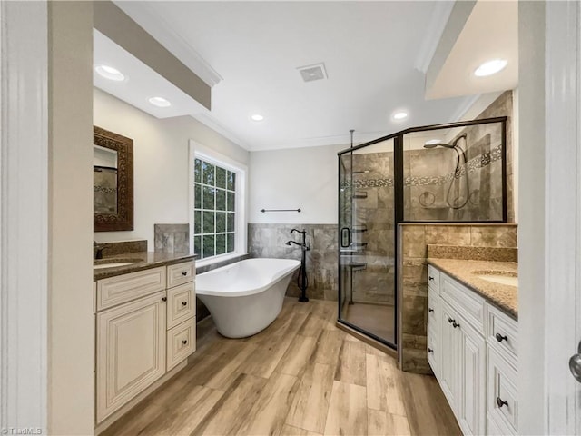 bathroom featuring wood-type flooring, plus walk in shower, tile walls, and vanity