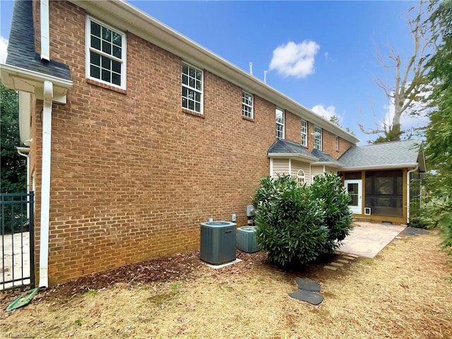 view of side of property featuring central AC, a patio, and a sunroom