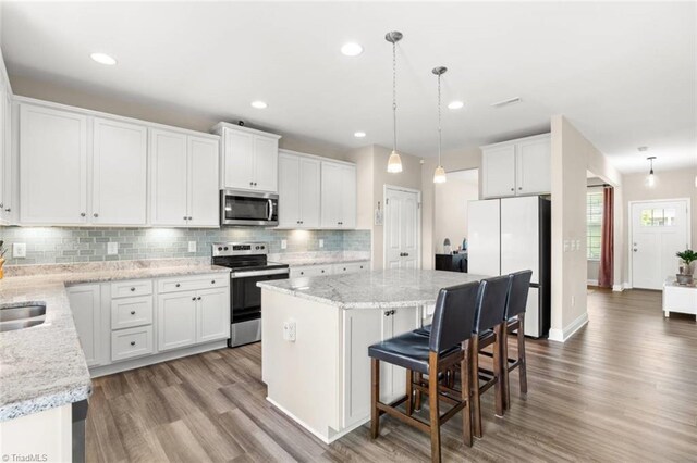 1827 Deveron Ct, Kernersville, NC 27284 - kitchen with stainless steel appliances, a center island, backsplash, wood finished floors, and white cabinetry