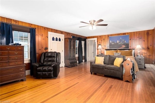 living room with wood-type flooring, wood walls, and ceiling fan