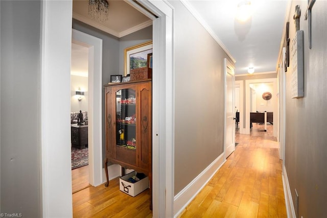 hall with ornamental molding and light hardwood / wood-style floors