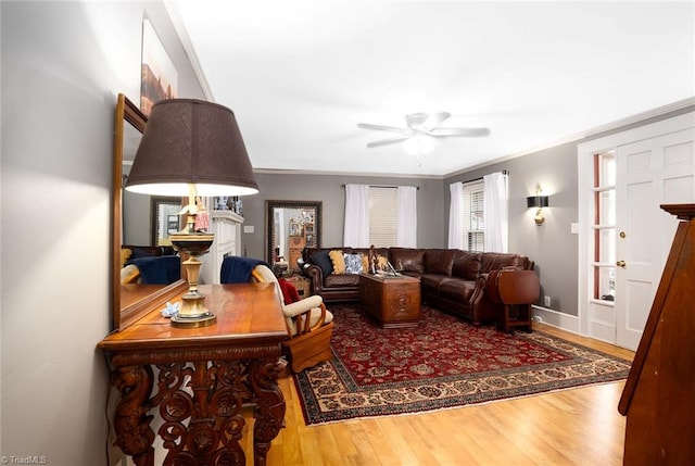 living room with ornamental molding, wood-type flooring, and ceiling fan