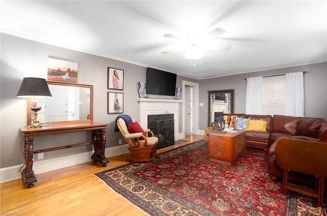 living room with ornamental molding, hardwood / wood-style floors, a high end fireplace, and ceiling fan