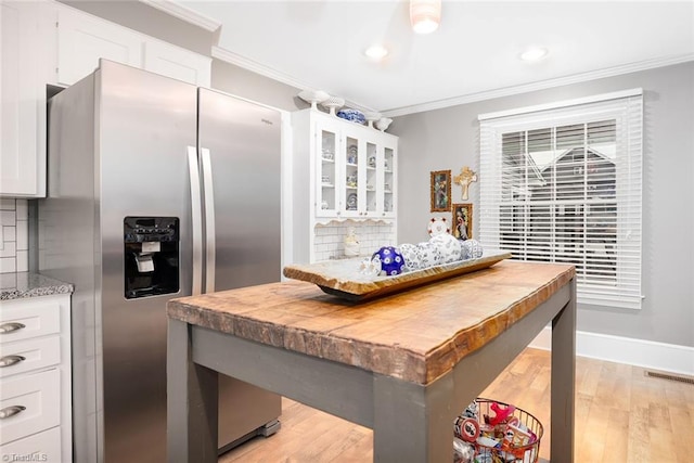 kitchen with backsplash, light wood-type flooring, stainless steel fridge, and white cabinetry