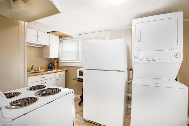 kitchen with light tile patterned flooring, sink, white cabinetry, white appliances, and stacked washer and clothes dryer