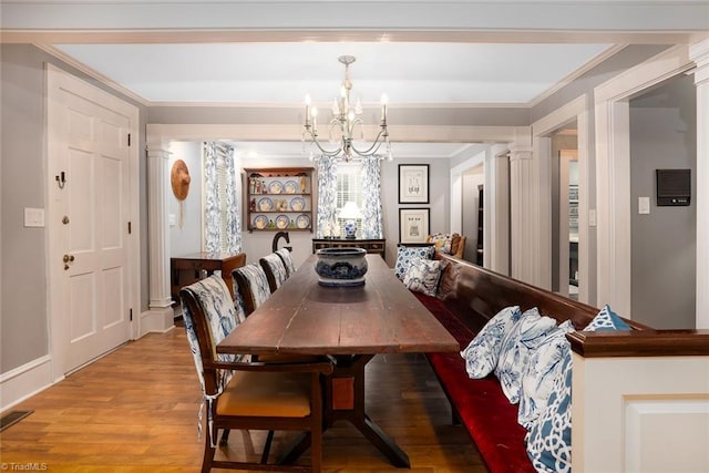 dining room featuring an inviting chandelier, light wood-type flooring, and decorative columns