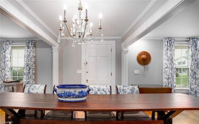 dining room featuring wood-type flooring, ornamental molding, an inviting chandelier, and ornate columns