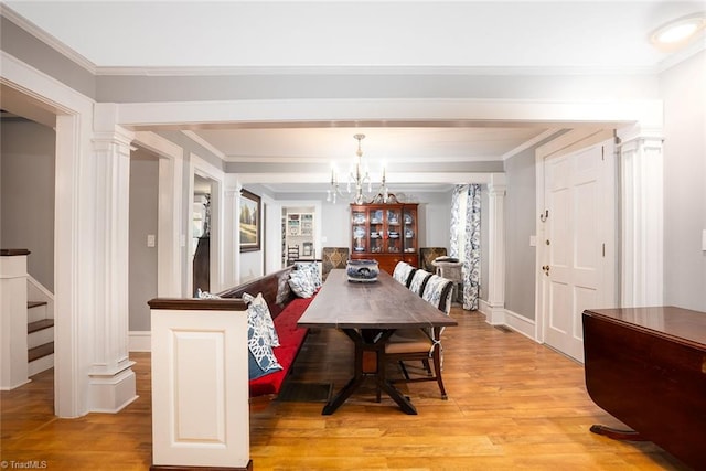 dining area featuring ornamental molding, a notable chandelier, light wood-type flooring, and ornate columns