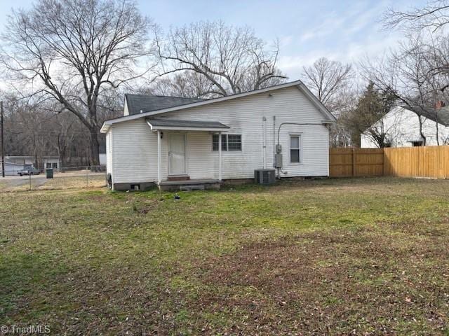 rear view of house with a yard, fence, and central AC unit