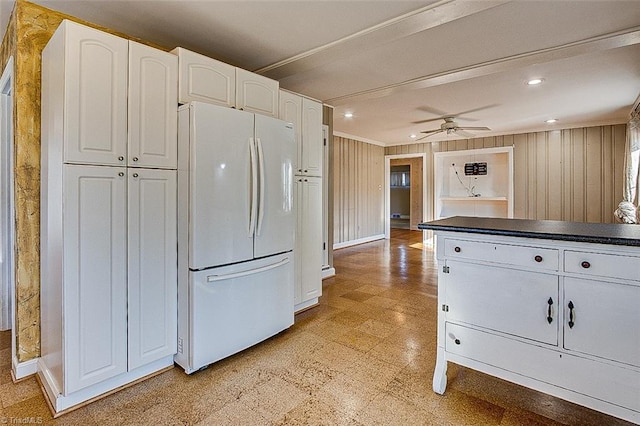 kitchen with white cabinets, ceiling fan, white refrigerator, and wood walls