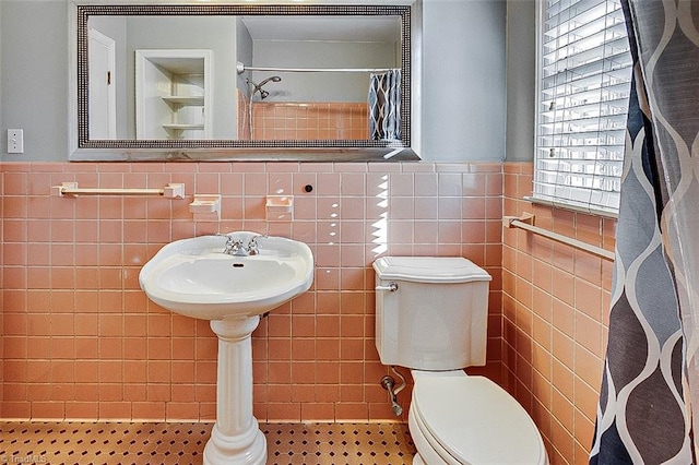 bathroom featuring tile patterned floors, curtained shower, tile walls, and toilet