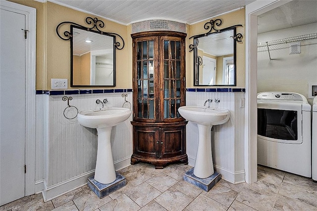 bathroom with tasteful backsplash, dual sinks, washer and clothes dryer, crown molding, and tile walls