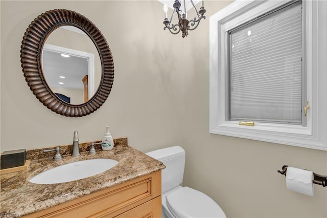 bathroom featuring toilet, a chandelier, and vanity