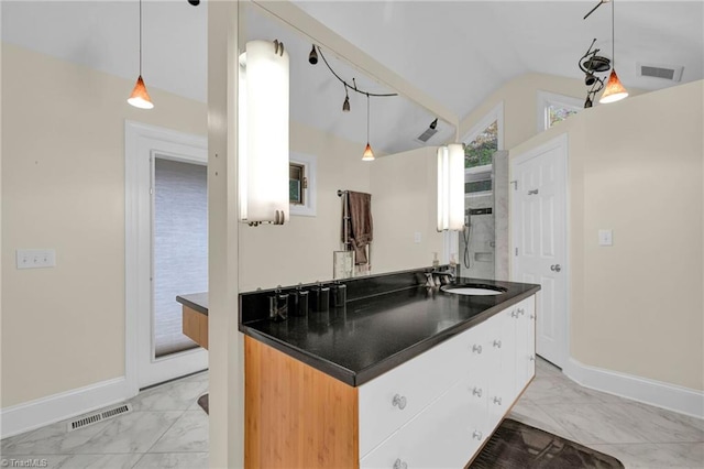 kitchen with sink, vaulted ceiling, hanging light fixtures, and white cabinets