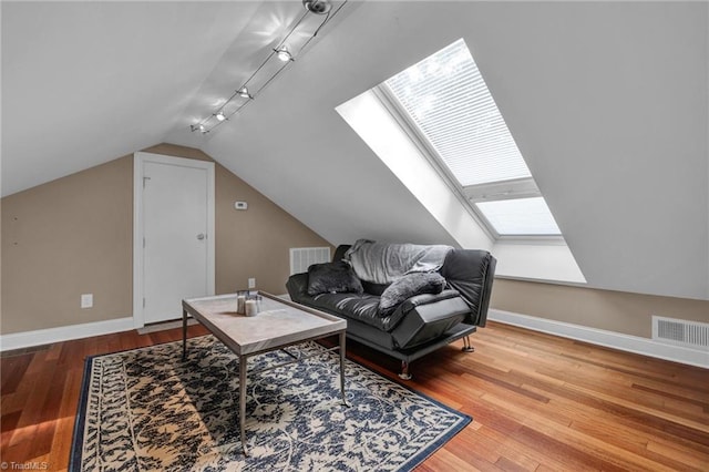 interior space featuring lofted ceiling with skylight, hardwood / wood-style flooring, and rail lighting