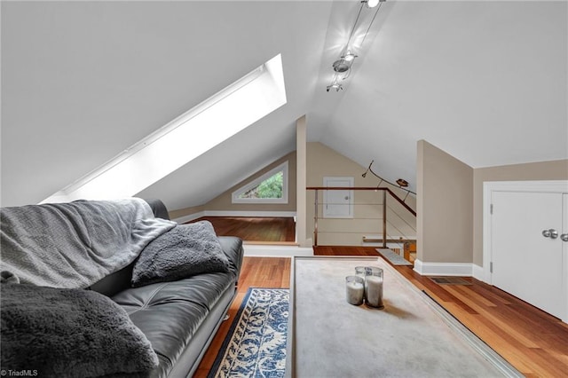 living room featuring vaulted ceiling with skylight and light wood-type flooring