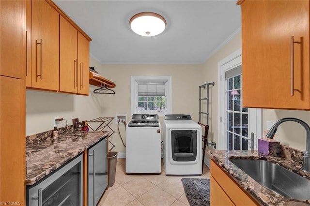 laundry area featuring sink, washing machine and clothes dryer, wine cooler, ornamental molding, and cabinets