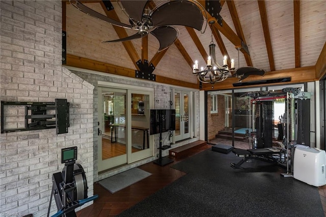 exercise room with dark hardwood / wood-style floors, a healthy amount of sunlight, high vaulted ceiling, and brick wall