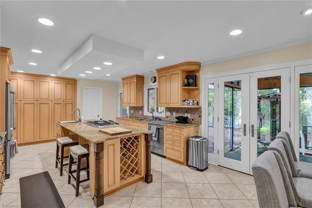 kitchen featuring french doors, appliances with stainless steel finishes, a kitchen island with sink, and backsplash