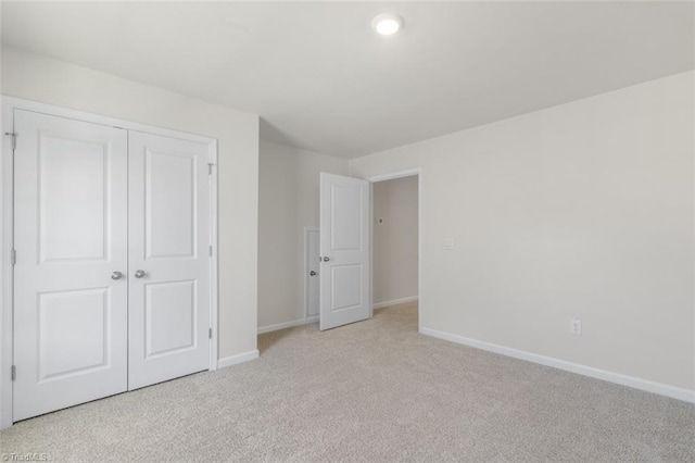 unfurnished bedroom featuring light colored carpet and a closet