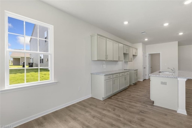 kitchen with gray cabinets, sink, light stone countertops, and light hardwood / wood-style flooring