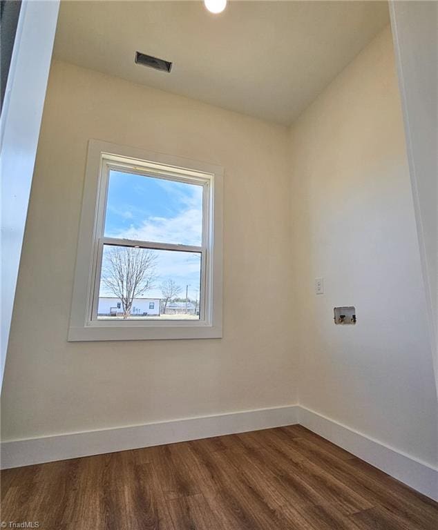 empty room featuring visible vents, dark wood finished floors, and baseboards