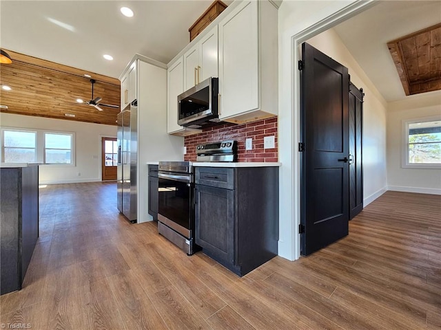 kitchen featuring stainless steel appliances, tasteful backsplash, light countertops, a barn door, and white cabinetry