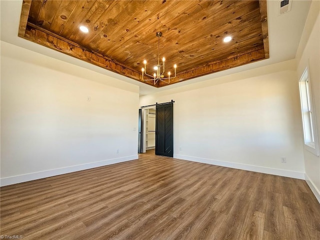 spare room with wood ceiling, a barn door, and a raised ceiling