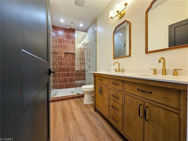 full bath with a tile shower, wood finished floors, a sink, and toilet