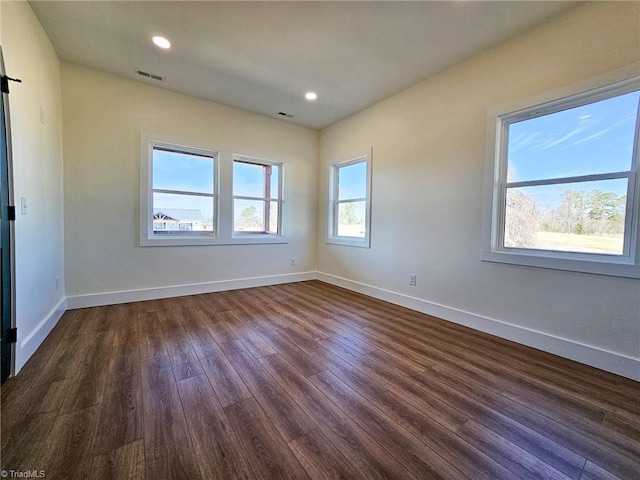 empty room featuring dark wood-style floors, visible vents, baseboards, and recessed lighting