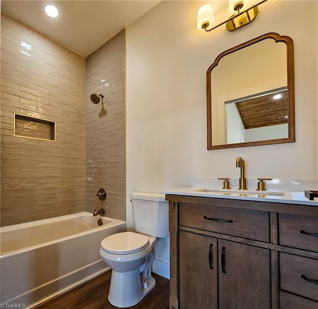 bathroom featuring toilet, vanity, wood finished floors,  shower combination, and baseboards