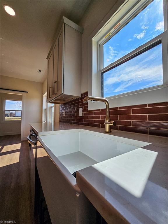 kitchen featuring dark wood-style floors, backsplash, a sink, and baseboards