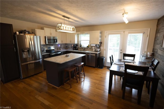 113 Stone Bridge Rd, Mount Airy, NC 27030 - kitchen with appliances with stainless steel finishes, a textured ceiling, a center island, a breakfast bar area, and dark wood-style flooring