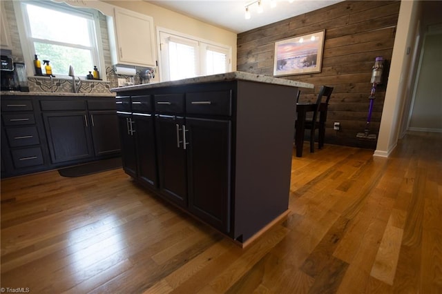 113 Stone Bridge Rd, Mount Airy, NC 27030 - kitchen featuring wooden walls, wood-type flooring, white cabinets, light stone counters, and a sink