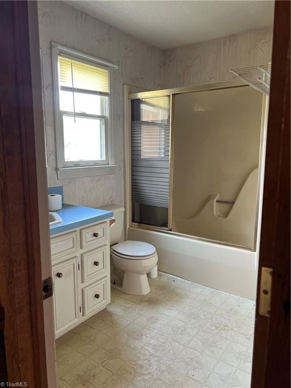 full bathroom with enclosed tub / shower combo, vanity, and toilet