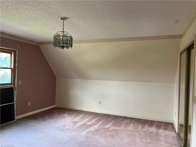 bonus room with a notable chandelier, a textured ceiling, vaulted ceiling, and carpet