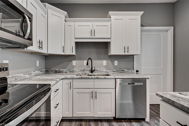 kitchen featuring a sink, appliances with stainless steel finishes, white cabinetry, and dark wood finished floors