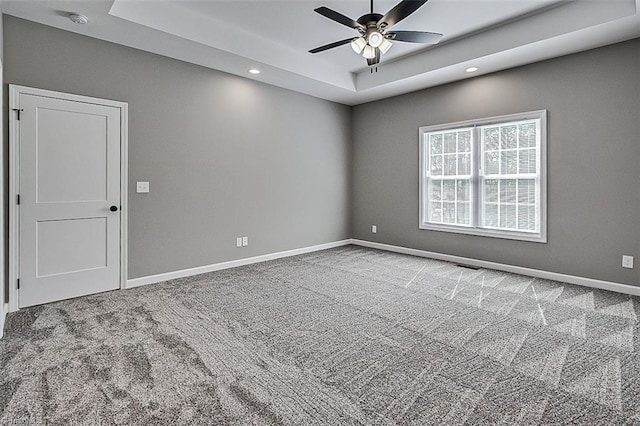carpeted spare room featuring a raised ceiling, ceiling fan, baseboards, and recessed lighting
