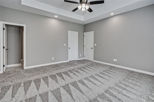 unfurnished bedroom featuring carpet floors, baseboards, recessed lighting, and a tray ceiling