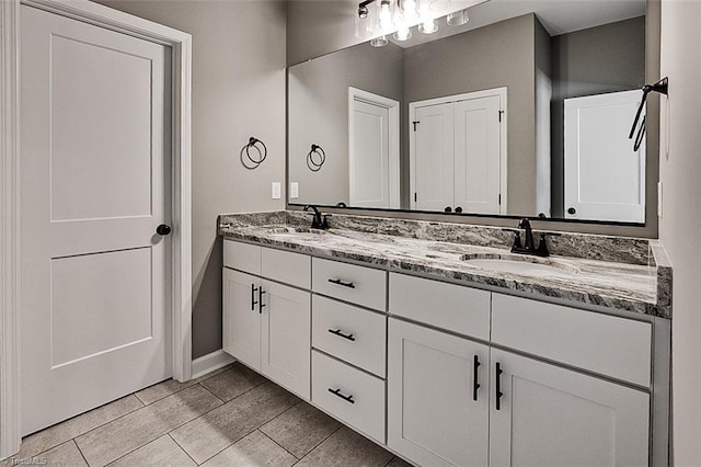 bathroom with a sink, baseboards, and double vanity