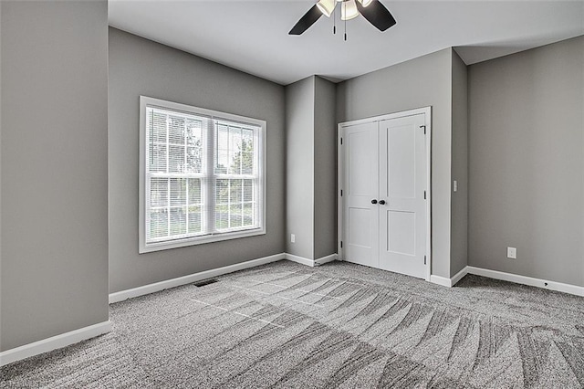 unfurnished bedroom featuring a closet, baseboards, visible vents, ceiling fan, and carpet