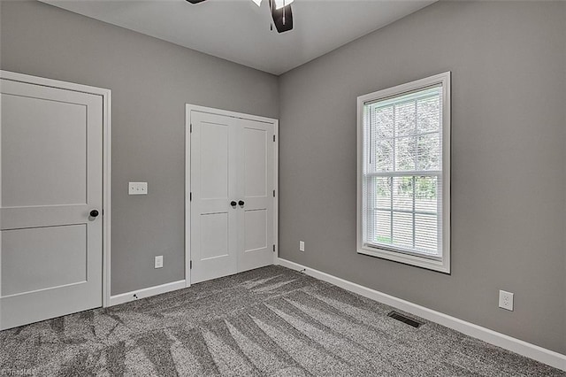 unfurnished bedroom with dark carpet, visible vents, baseboards, and multiple windows