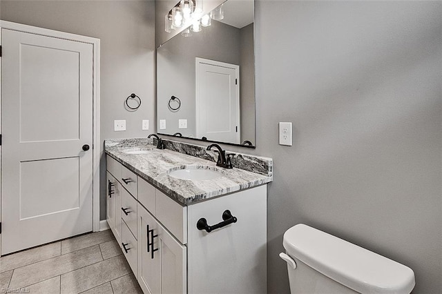 bathroom with toilet, tile patterned floors, double vanity, and a sink