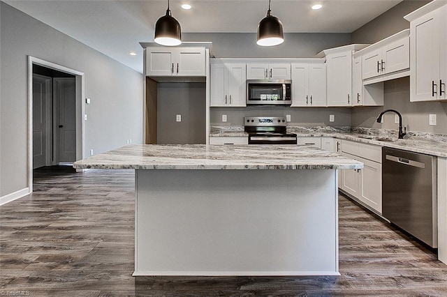 kitchen featuring appliances with stainless steel finishes, a sink, white cabinetry, and a kitchen island