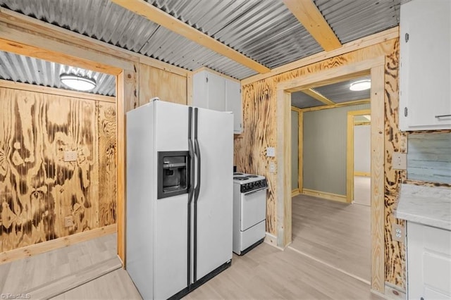 539 W Salisbury St, Denton, NC 27239 - kitchen featuring white appliances, light countertops, light wood-style flooring, wooden walls, and white cabinetry