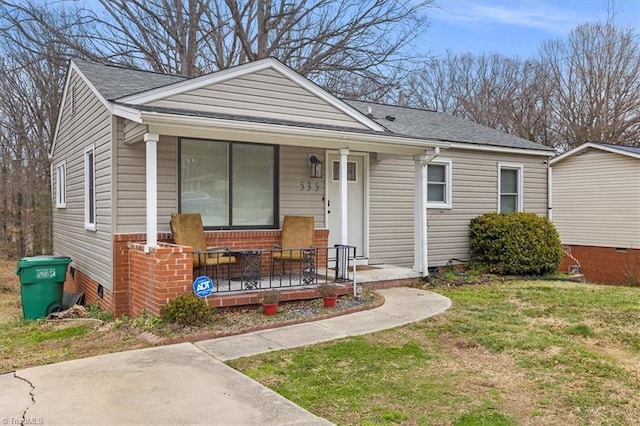 bungalow-style home featuring roof with shingles, a porch, and a front lawn